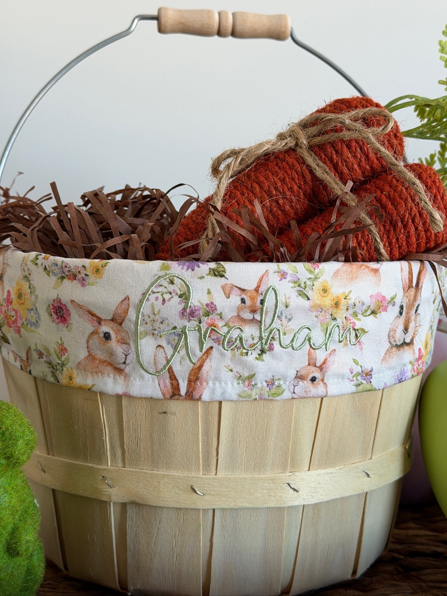 Wooden Easter basket with floral fabric liner, straw, and red burlap eggs.