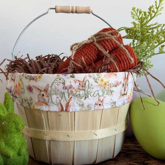 Decorative Easter basket with floral liner, red eggs, and green apple on a woven surface.