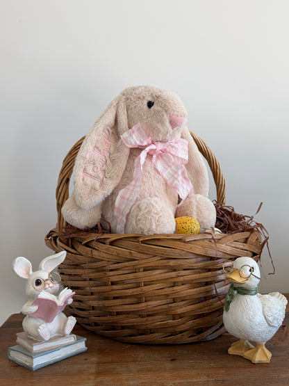 Wicker basket with plush bunny, small rabbit figurine, and duck on a wooden surface.
