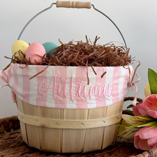 Wooden basket with pink checkered liner, Easter eggs, and flowers on a light background