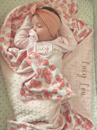 Newborn baby wrapped in a pink and white floral blanket with 'Lucy Lou' branding.